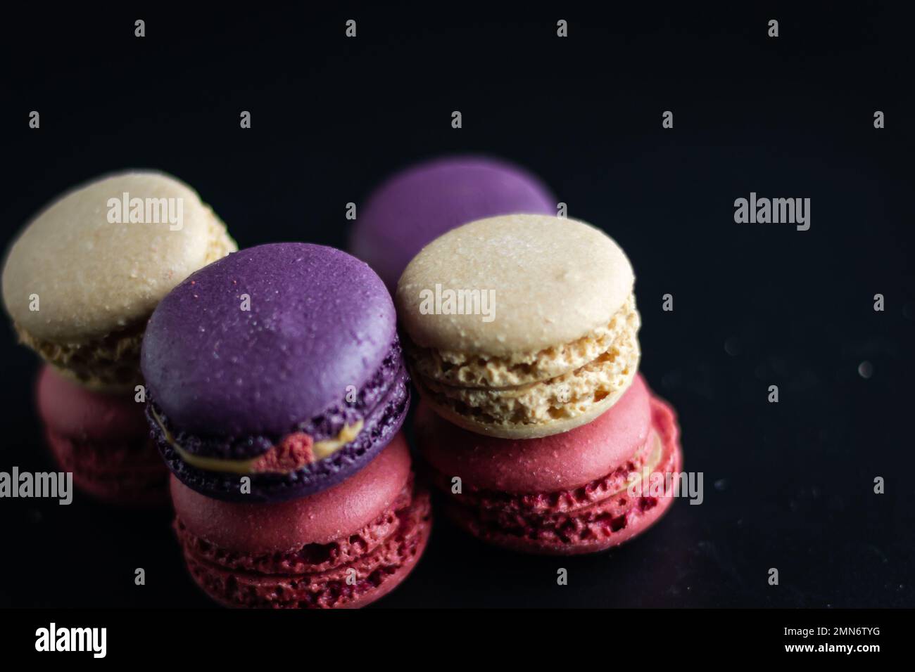 mini macaron de couleur différente sur fond sombre Banque D'Images