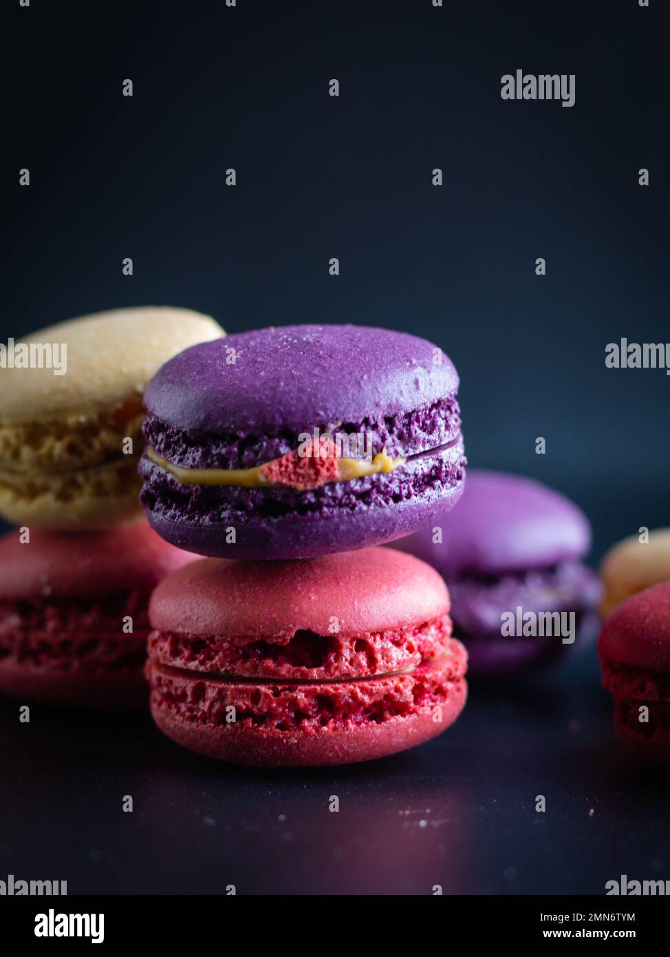 mini macaron de couleur différente sur fond sombre Banque D'Images