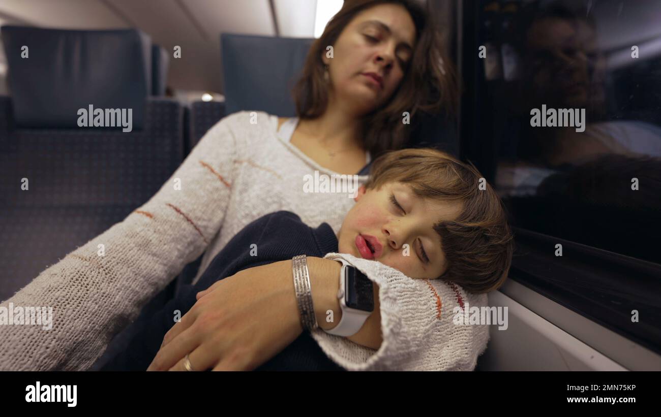 Mère et enfant dormant dans le train. Un parent bâille tout en tenant le petit garçon dans les bras qui se nouent pendant le voyage Banque D'Images