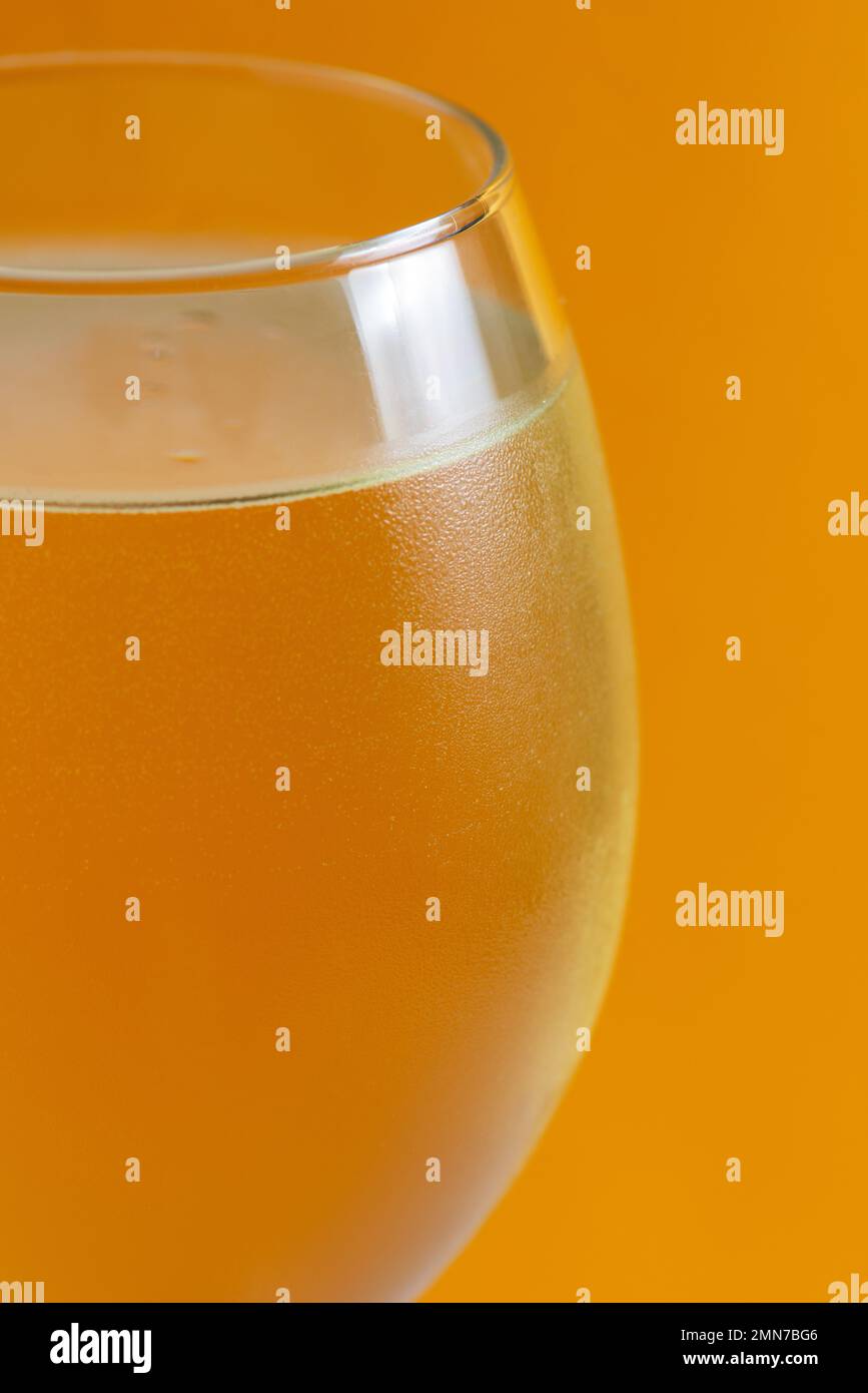 Vin blanc dans un verre de glace avec des bulles sur fond jaune, dans le bar à boissons photo studio de haute qualité Banque D'Images