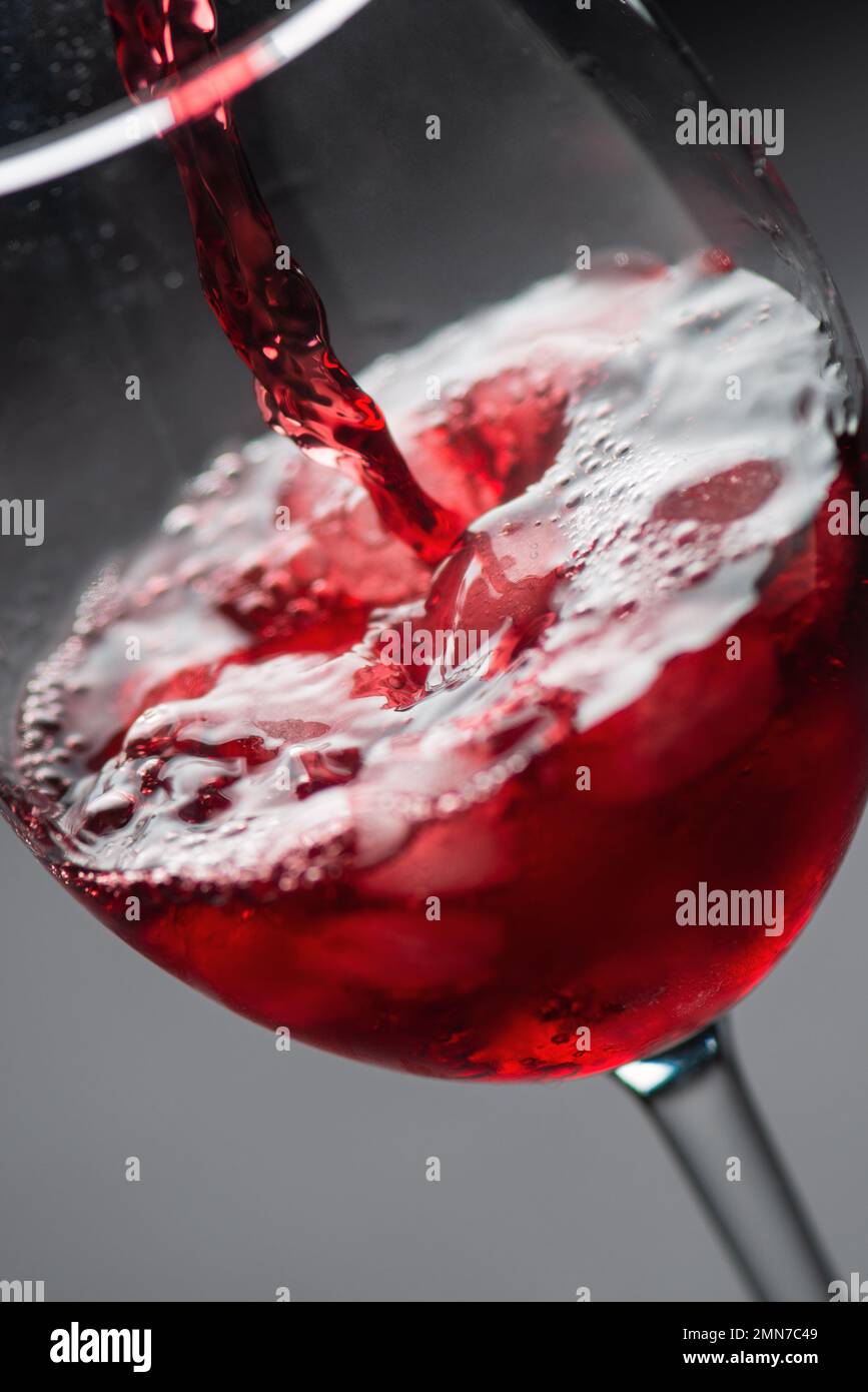 Verser du vin rouge dans un verre de glace avec des bulles, photo studio de haute qualité, gros plan Banque D'Images