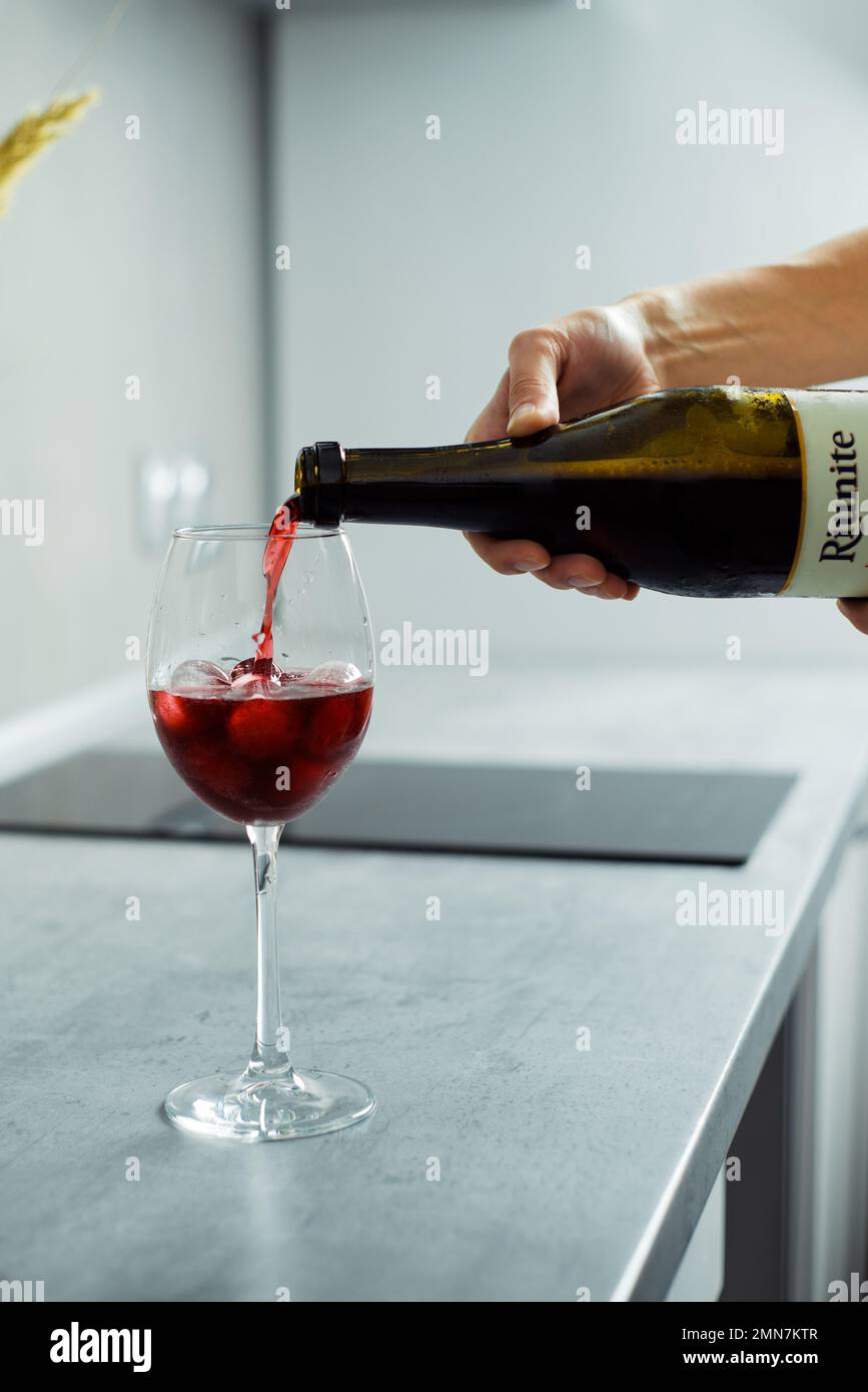 La main de la femme verse du vin rouge dans des verres avec de la glace sur la table à la maison, gros plan Banque D'Images