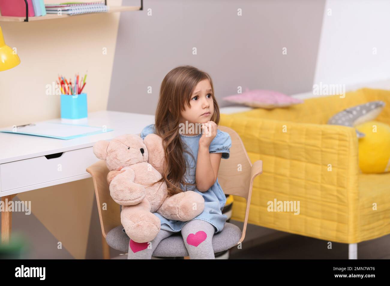 Adorable petite fille jouant avec un ours jouet à la maison Banque D'Images