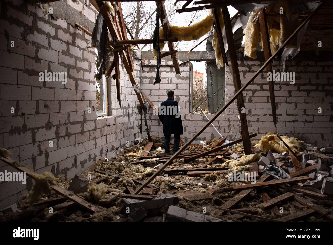 Un homme traverse une pièce dans un bâtiment bombardé sur l'île de Kherson, à quelques kilomètres du territoire occupé par la Russie. L'île de Kherson est la frontière entre le territoire ukrainien et le territoire russe. La plupart de sa population s'est enfui et ce qui reste sont des chiens et des chats abandonnés et des maisons qui sont en train de pourrir lentement de la pluie et de l'humidité qui entre par les trous dans les toits et les murs en raison de la constante pilonnage. Banque D'Images