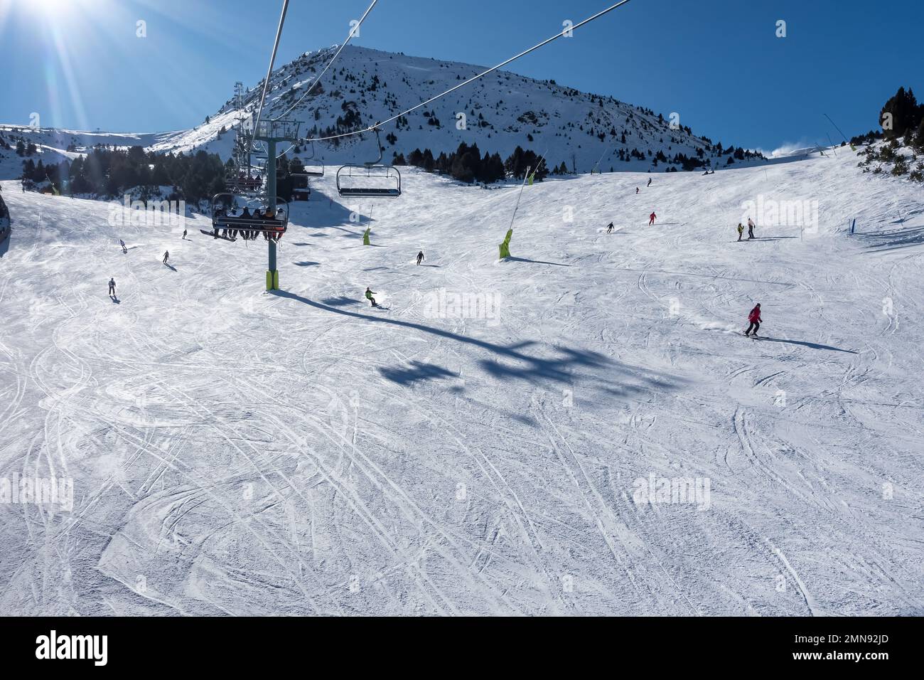 Piste de ski avec les skieurs qui glissent sur la pente dans les Pyrénées, Andorre, photo avec copyspace. Banque D'Images