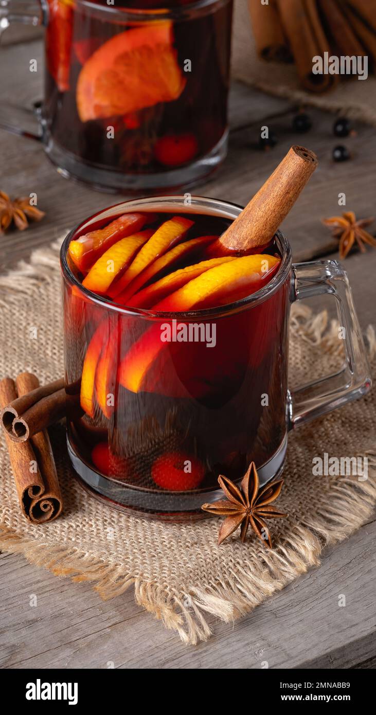Vin chaud dans des mugs en verre avec des épices et des agrumes sur un vieux bois Banque D'Images