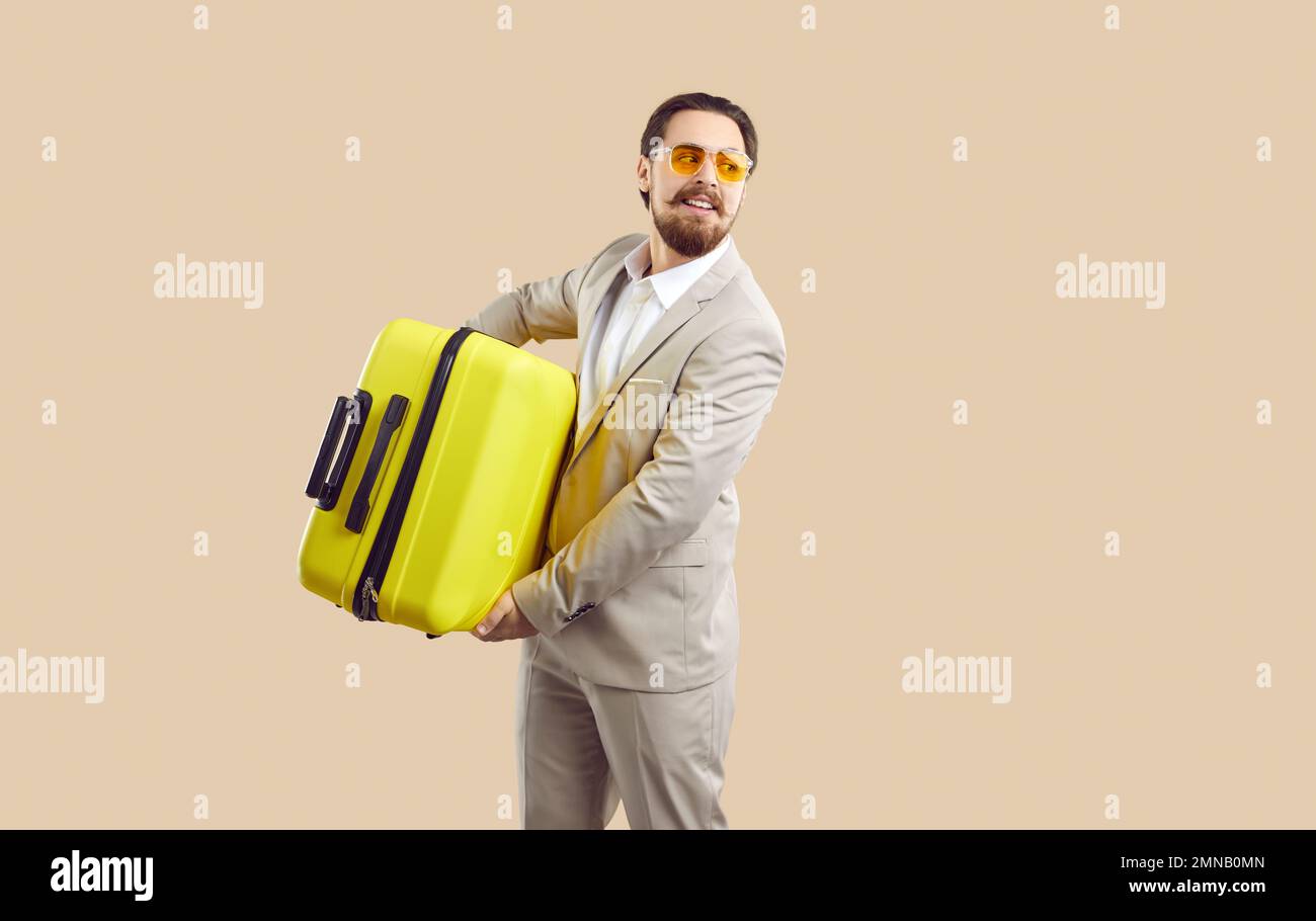 Un homme d'affaires avec une valise de voyage jaune se rend en voyage d'affaires ou en vacances tant attendues. Banque D'Images