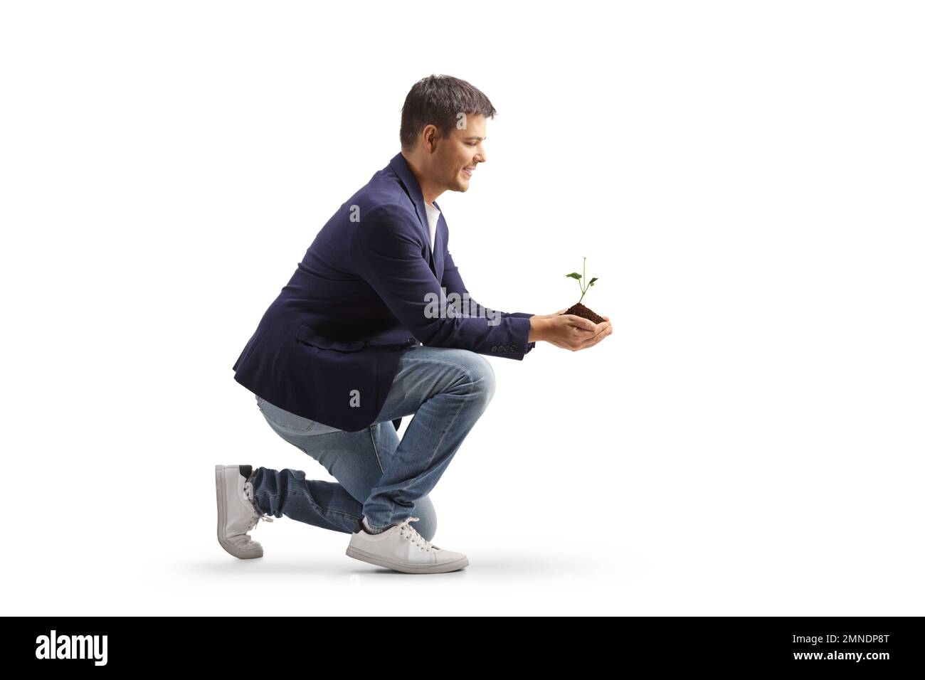 Homme s'agenouillant et tenant une jeune plante et la terre dans ses mains isolées sur fond blanc Banque D'Images