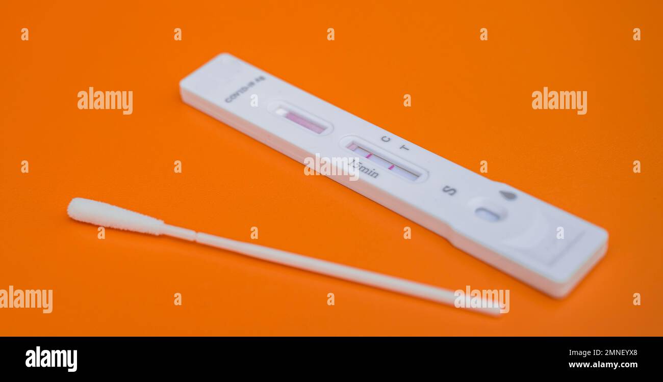 Cassette de test et écouvillon, kit de test d'antigène Covid-19, résultat de test positif, auto-test, SRAS-COV-2, virus Corona, pandémie, fond orange Banque D'Images