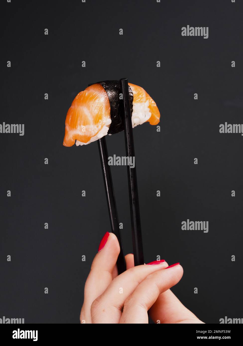 femme tenant une paire de baguettes avec des sushis de saumon.Résolution et superbe photo de haute qualité Banque D'Images