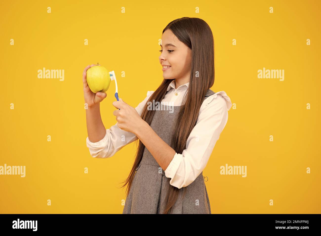 Vitamines de pomme pour des dents saines. Portrait de la jeune fille caucasienne tient une brosse à dents se brossant ses dents, routine du matin, hygiène dentaire, isolé dessus Banque D'Images