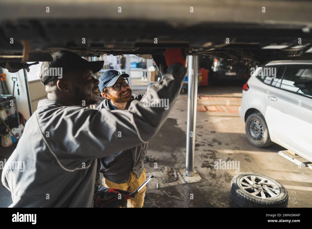 Les mécaniciens portant des gants remplaçant les pneus d'une voiture sur un ascenseur dans un atelier de réparation automobile. Photo de haute qualité Banque D'Images