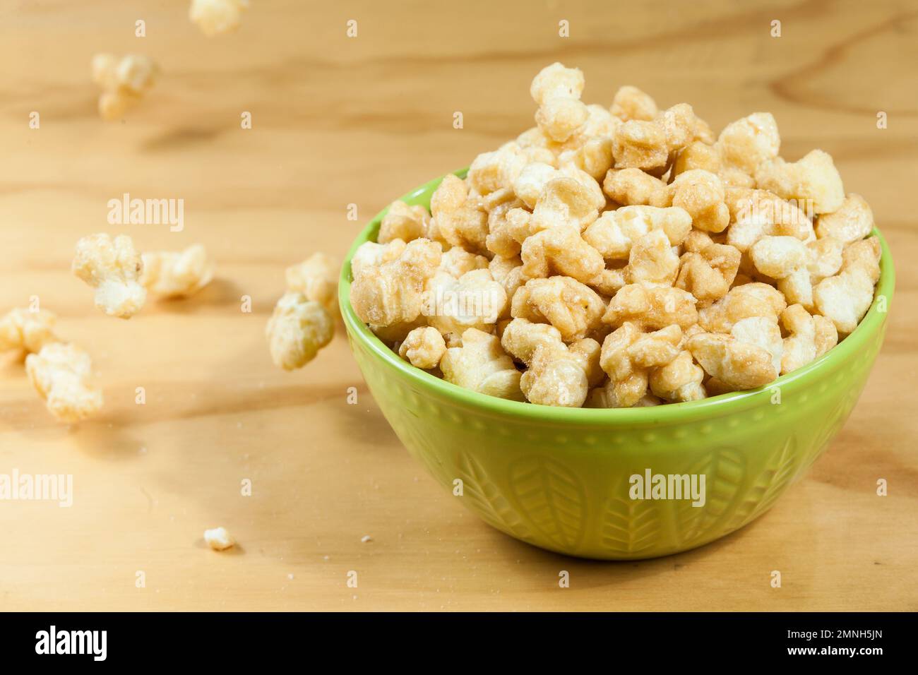 Un bol de popcorn caramélisé savoureux ; sur fond de bois. Banque D'Images