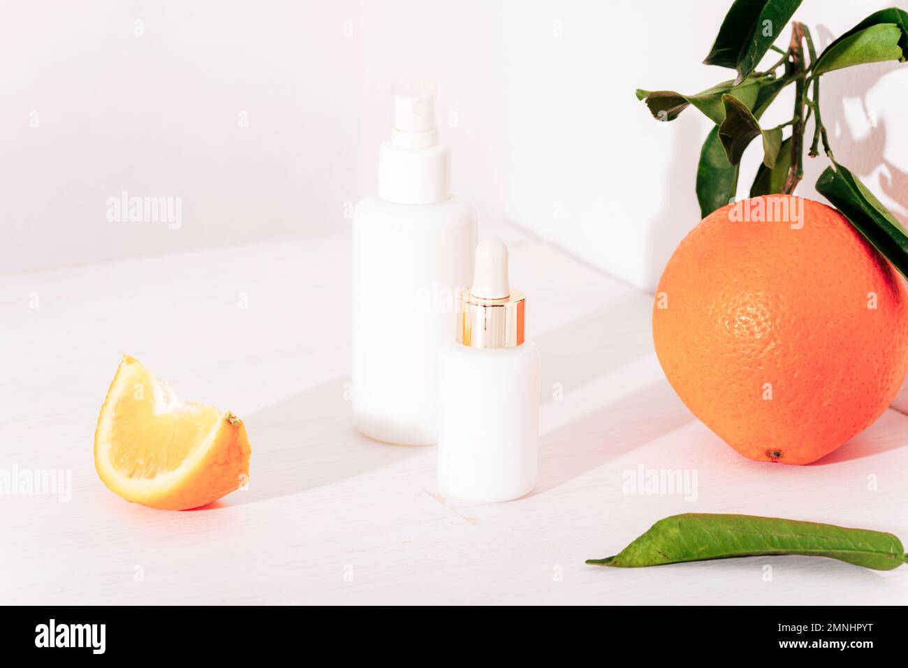 Flacons de sérum à usage cosmétique et fruits orange sur fond blanc. Concept de cosmétiques naturels, maquette Banque D'Images