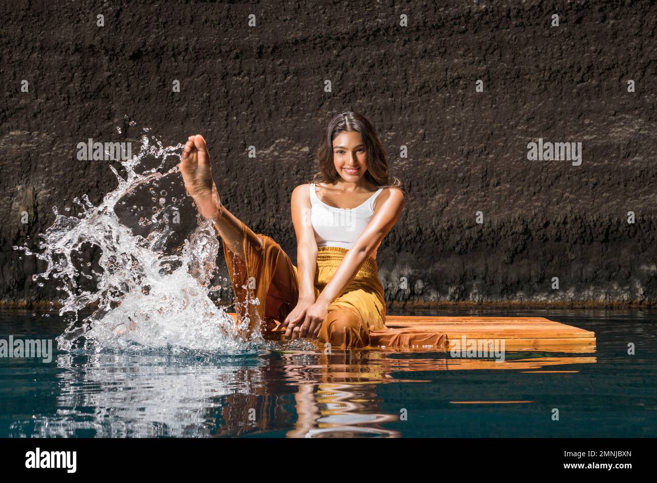 Belle femme barbotant de l'eau sur un radeau en bois au cenote Banque D'Images