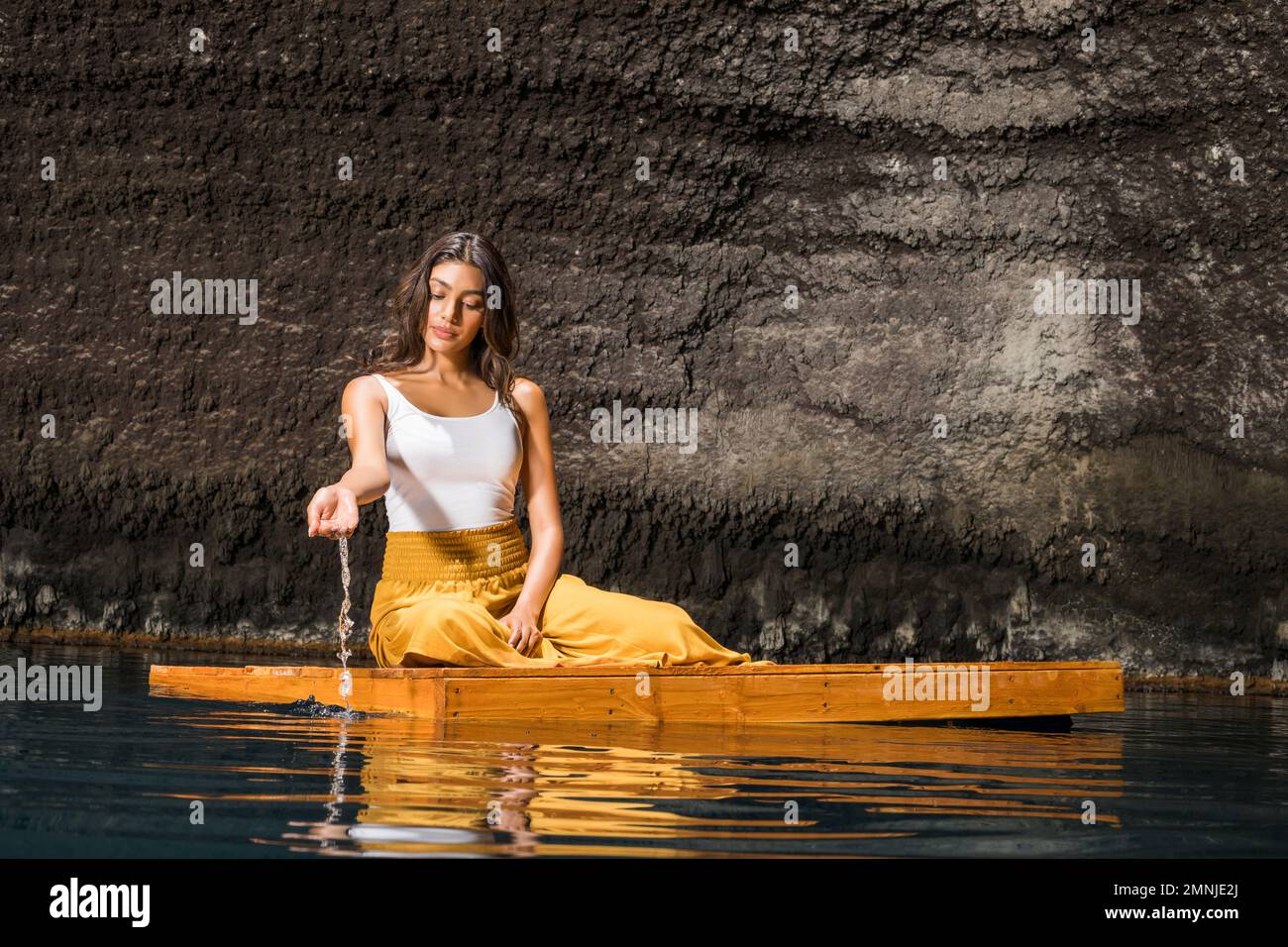Belle femme assise sur un radeau en bois sur l'étang Banque D'Images