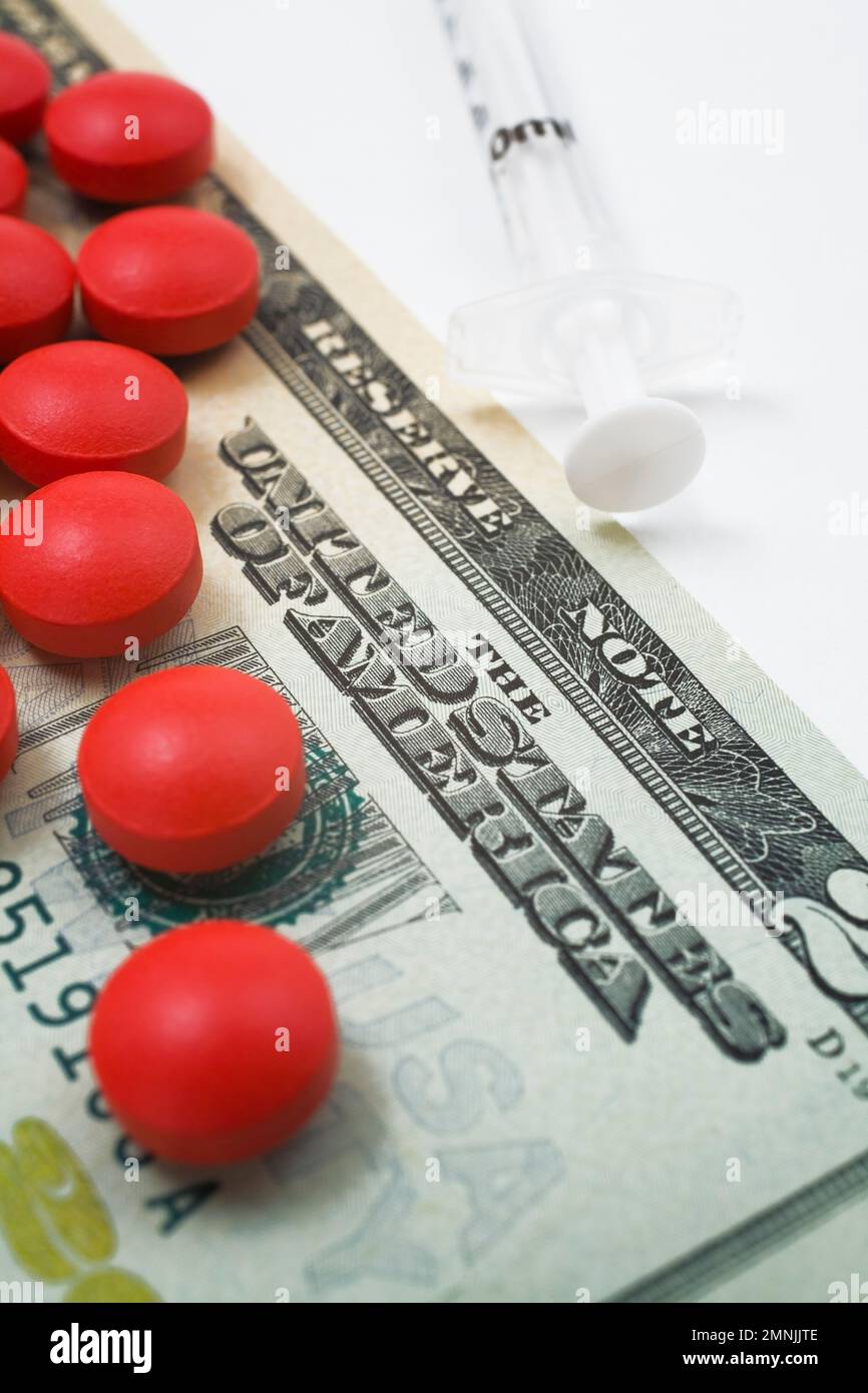 Pilules de médecine rouge sur le dessus du billet de vingt dollars US à côté de la seringue. Banque D'Images