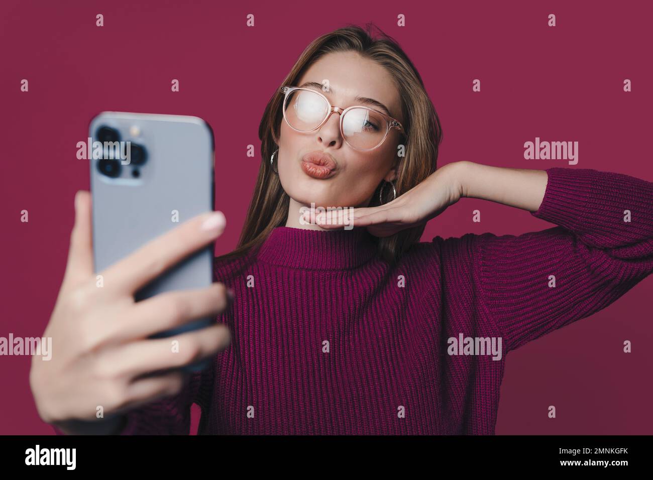 Portrait d'une belle femme brunette-cheveux attrayante prenant le selfie envoyant un baiser d'air isolé sur un fond de couleur cramoisi Banque D'Images
