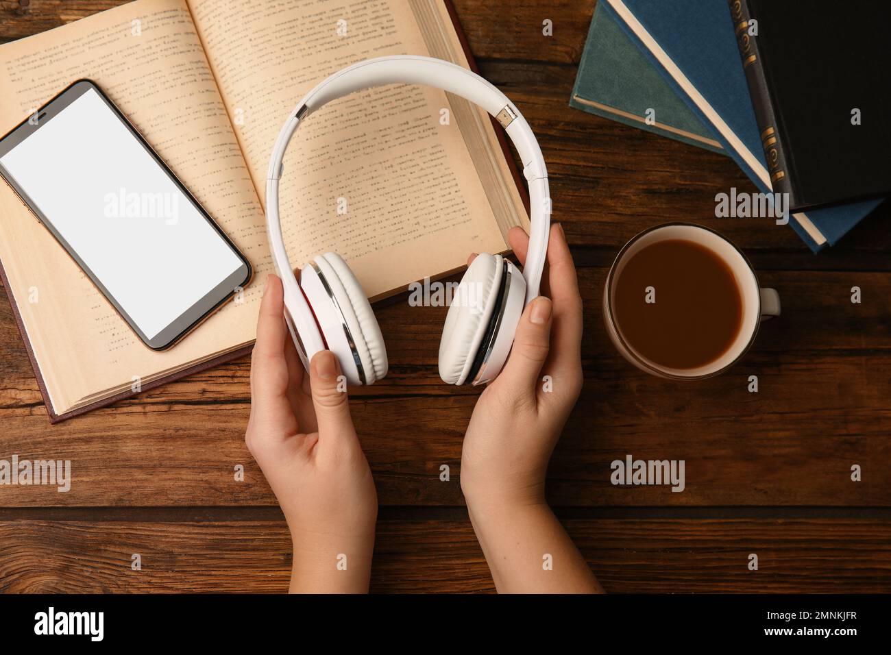 Femme tenant un casque sur une table en bois avec des livres, vue de dessus Banque D'Images