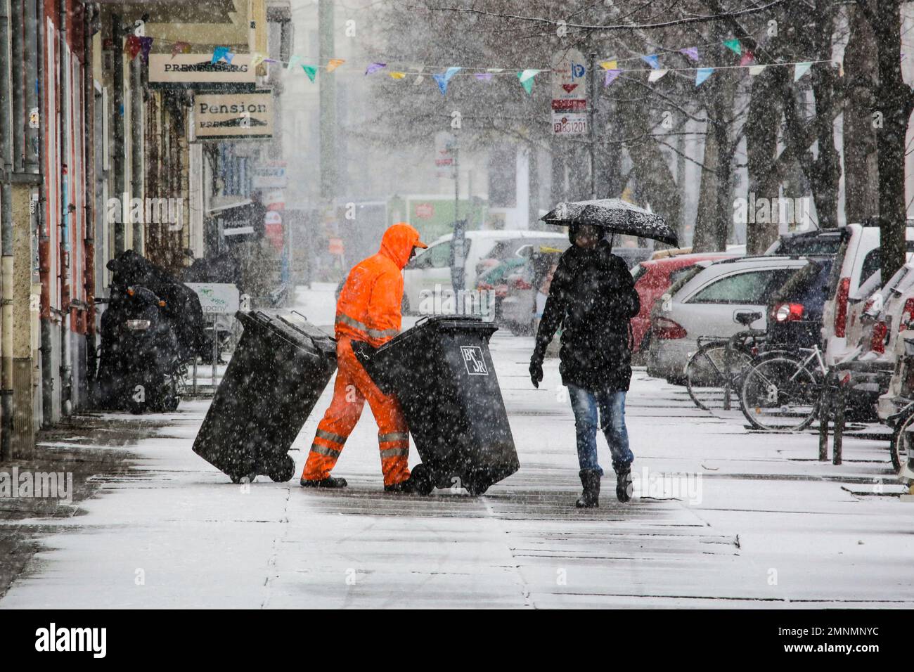 A trash collector moves garbage bins on a snow covered sidewalk in Berlin, Germany, Tuesday, March 20, 2018. (AP Photo/Markus Schreiber) Banque D'Images