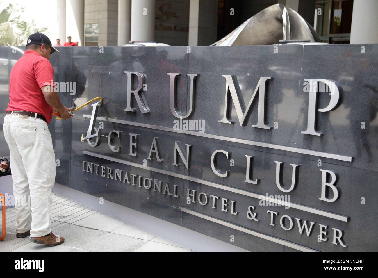 In this March 5, 2018 photo, a man removes the word Trump, off a marquee outside the Trump Ocean Club International Hotel and Tower in Panama City. Lawyers for President Donald Trump’s family hotel business threatened a Panamanian judicial official handling a dispute related to Trump Hotels’ management of a 70-story luxury hotel, according to a complaint filed with the anticorruption division of Panama’s chief prosecutor. (AP Photo/Arnulfo Franco) Banque D'Images