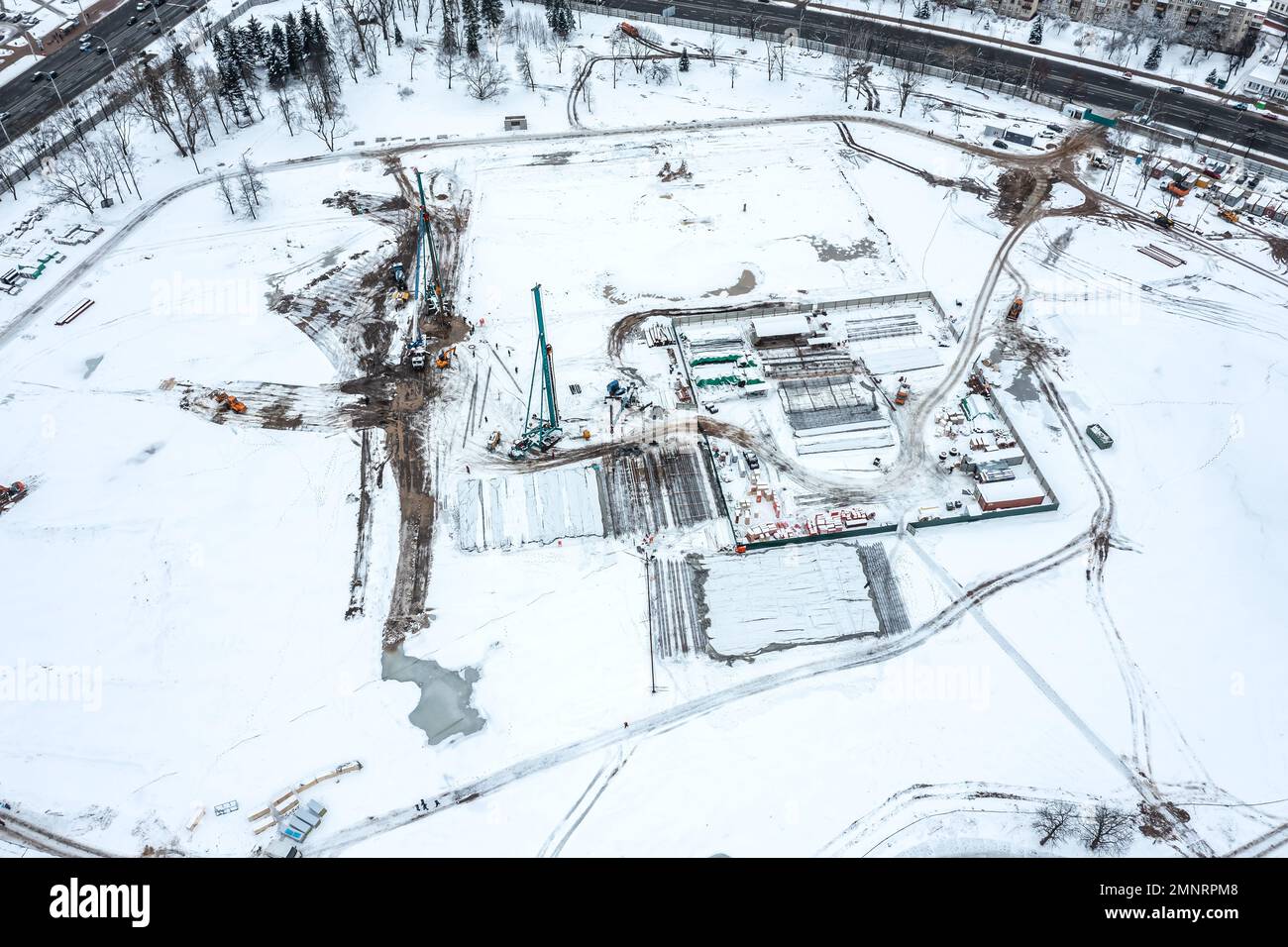 nouveau site de construction avec des conducteurs de pieux de travail et des matériaux de construction empilés. vue aérienne en hiver. Banque D'Images