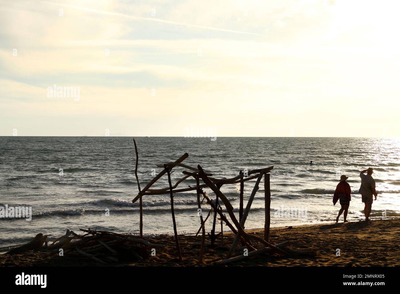 Driftwood construction et 2 personnes marchant le long de la plage de Parco Naturale della Maremme, province Grosseto, Toscane, Italie Banque D'Images