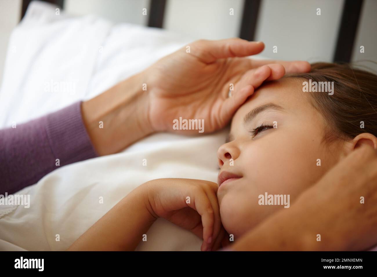 L'amour est assis toute la nuit avec un enfant malade. une mère attentionnée sentant le front de sa petite fille malade. Banque D'Images