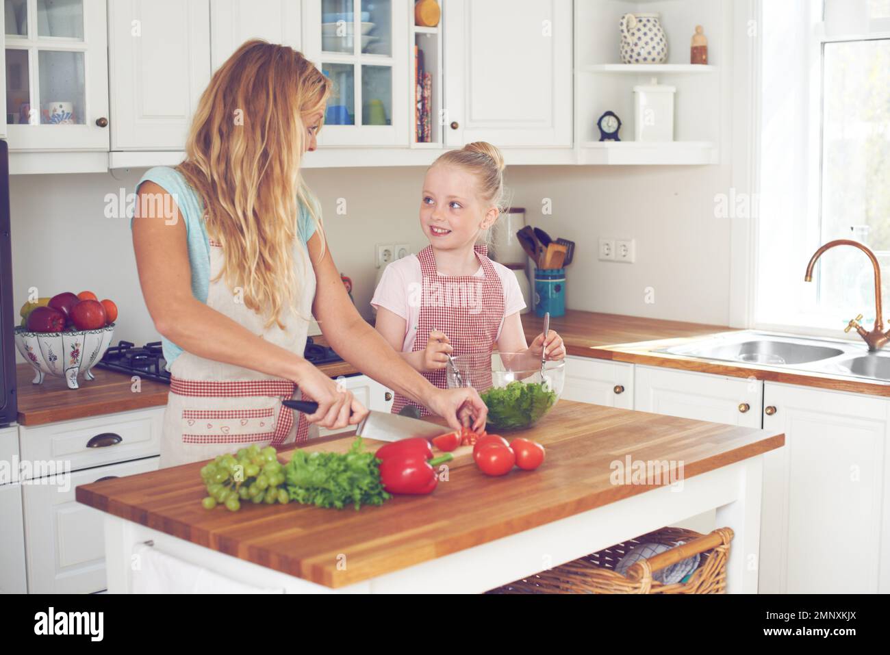 Préparer une salade savoureuse. Une jeune mère et sa fille font une salade ensemble. Banque D'Images