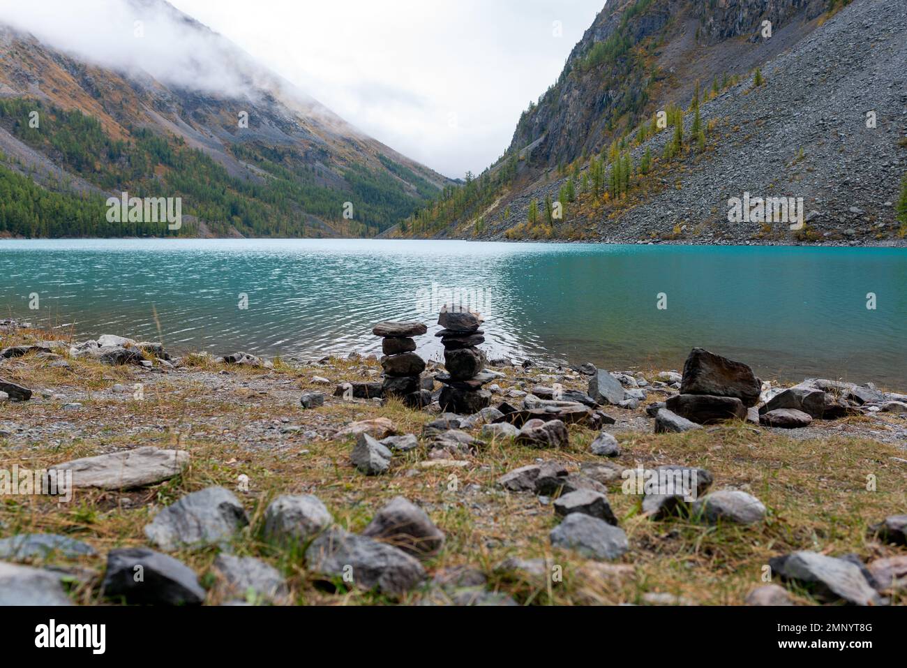 Des pierres empilées les unes sur les autres sur fond de brouillard surpassent les sommets d'une forêt d'épicéa après la pluie sur le lac Banque D'Images