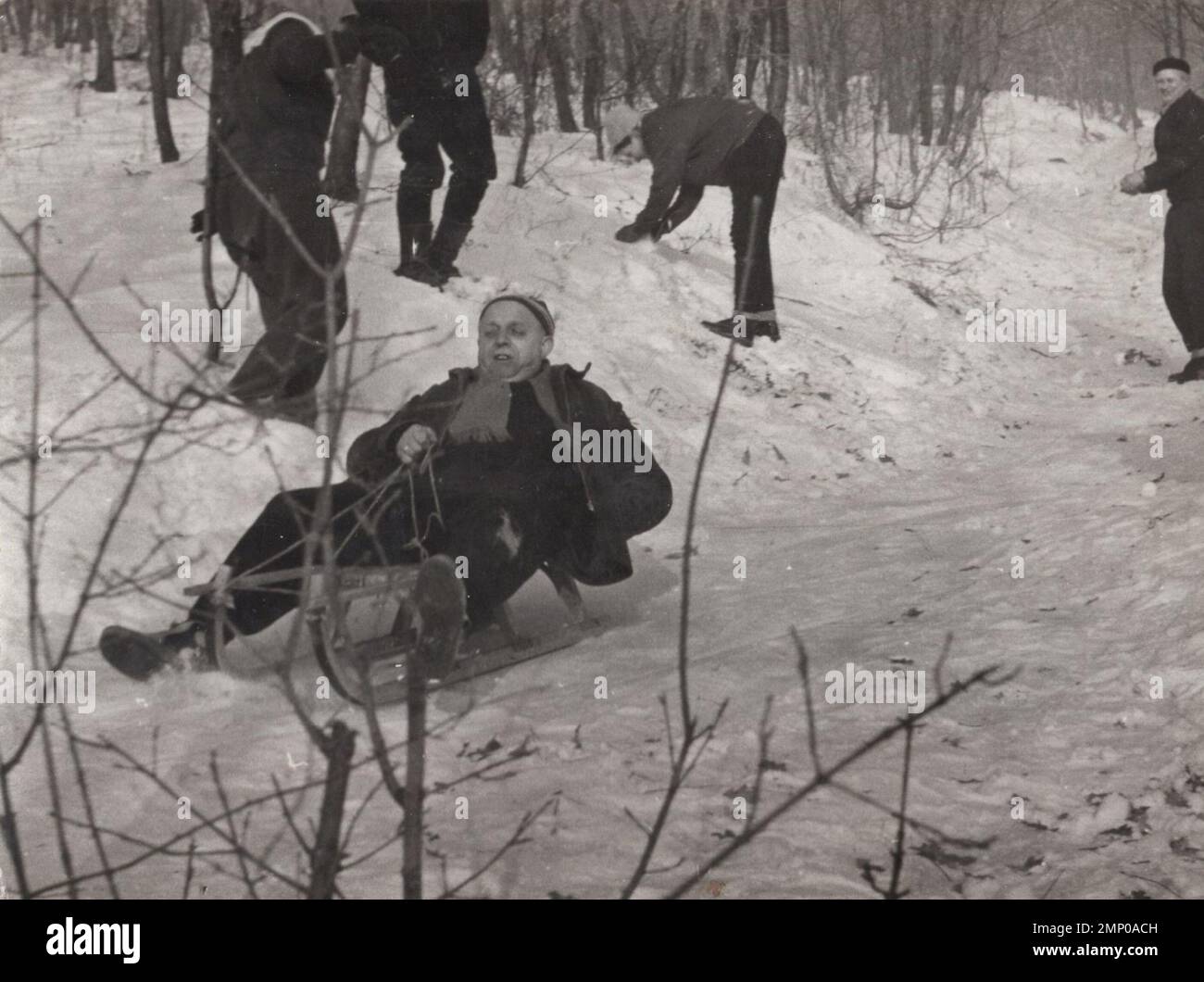 moment vintage / moment drôle vintage / photo vintage / puissance du moment / moments magiques / un homme très courageux ( sérieusement un héros ) est en train de traînder une colline enneigée au 1940s. Il est attaqué pendant qu'il glisse, un autre people combat le ballon de neige et il est la cible. Banque D'Images