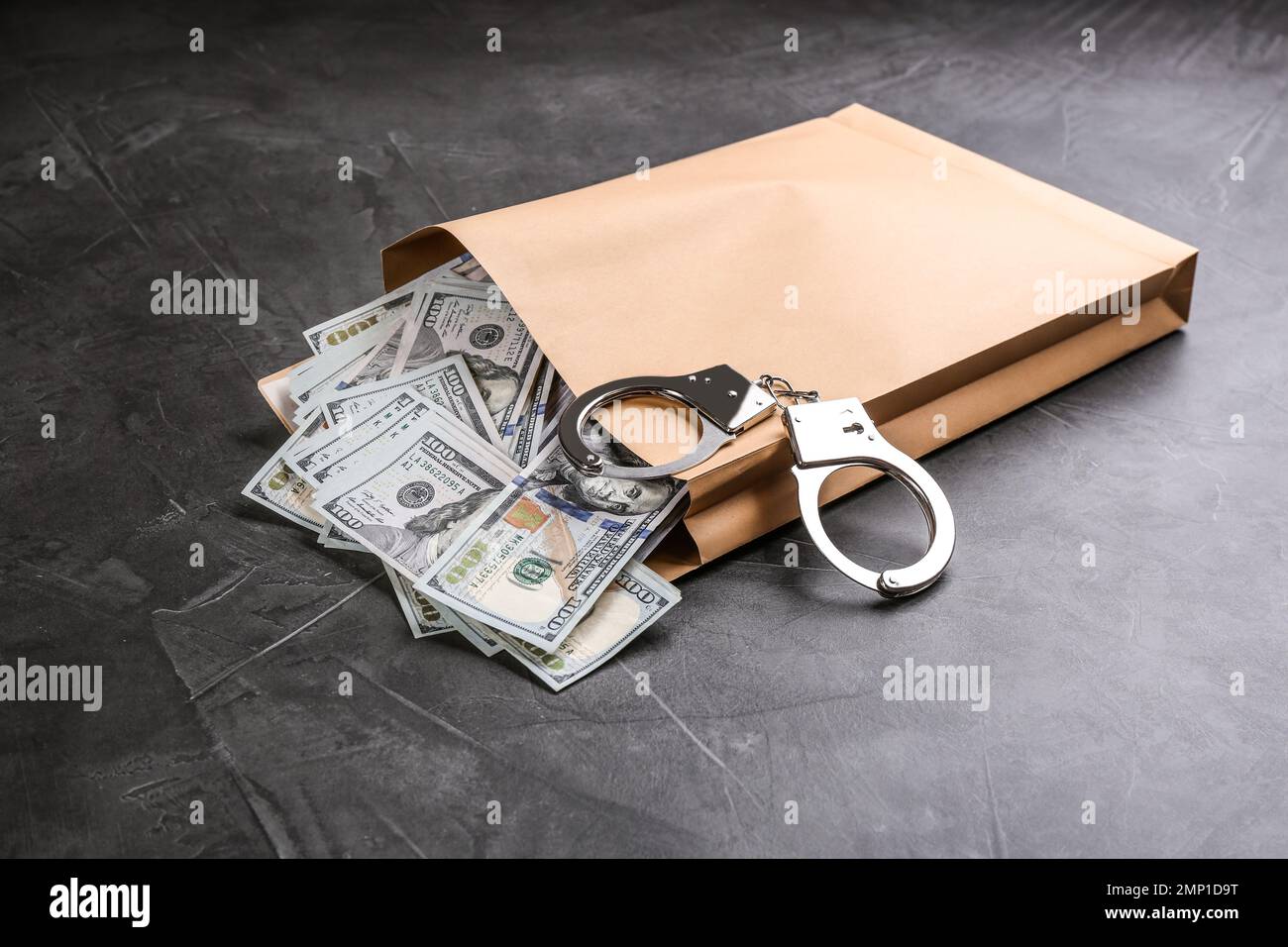 Enveloppe avec billets et menottes sur table en pierre grise. Concept de corruption Banque D'Images