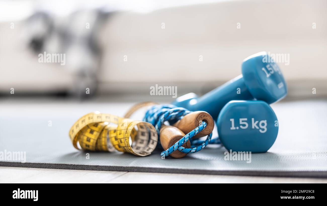 Corde de saut et mètre ruban sur le tapis à la maison dans la salle de séjour. Concept de mode de vie sain. Banque D'Images