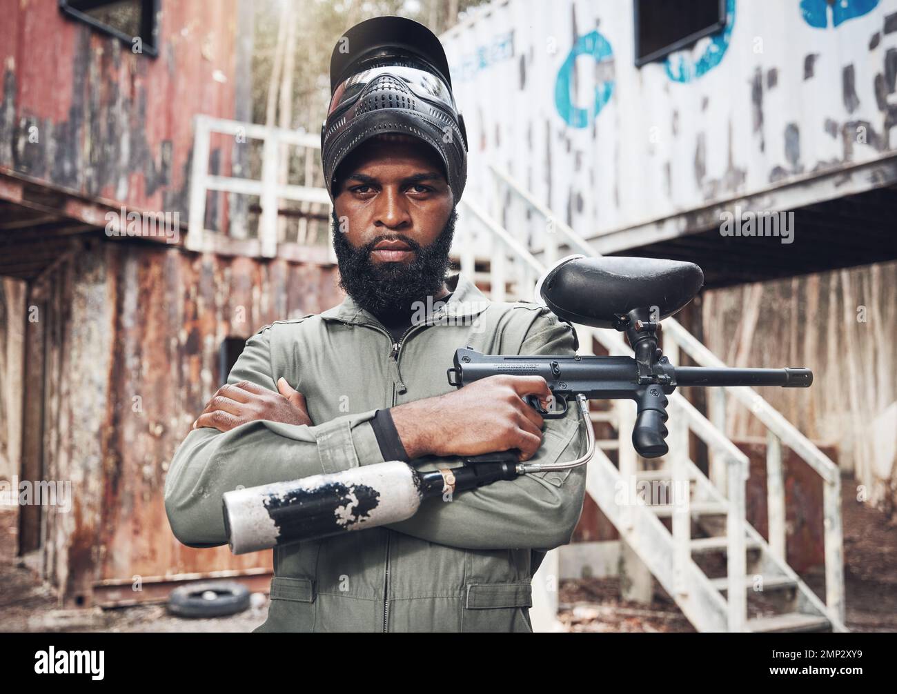 Bras croisés, portrait et homme noir avec un pistolet à paintball pour la remise en forme, l'entraînement ou un jeu. Exercice, concentration et joueur africain sérieux avec un fusil pour Banque D'Images