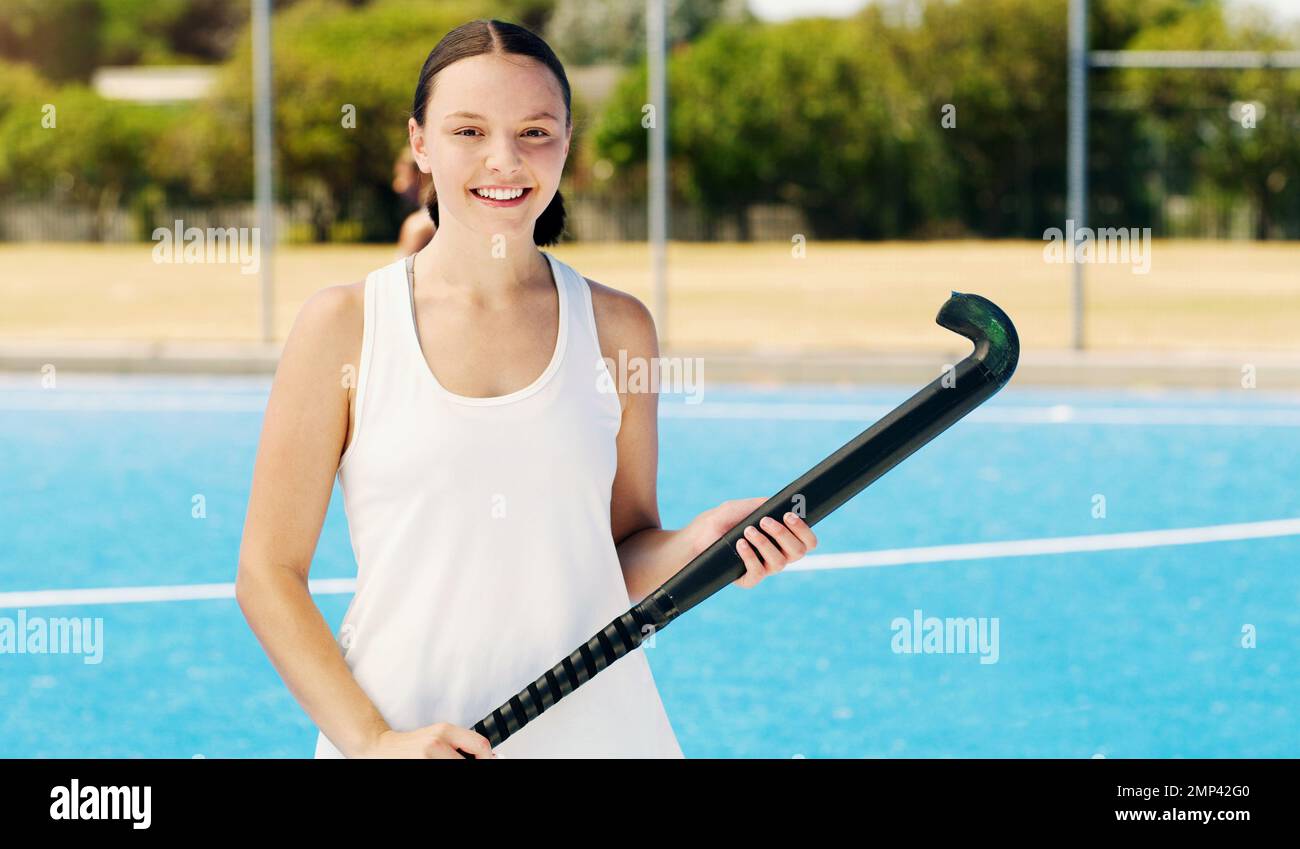 Portrait, fille de hockey et terrain avec sourire, foyer ou vision à l'entraînement en plein air pour la future carrière sportive. Bonne femme, entraînement sportif ou exercice Banque D'Images