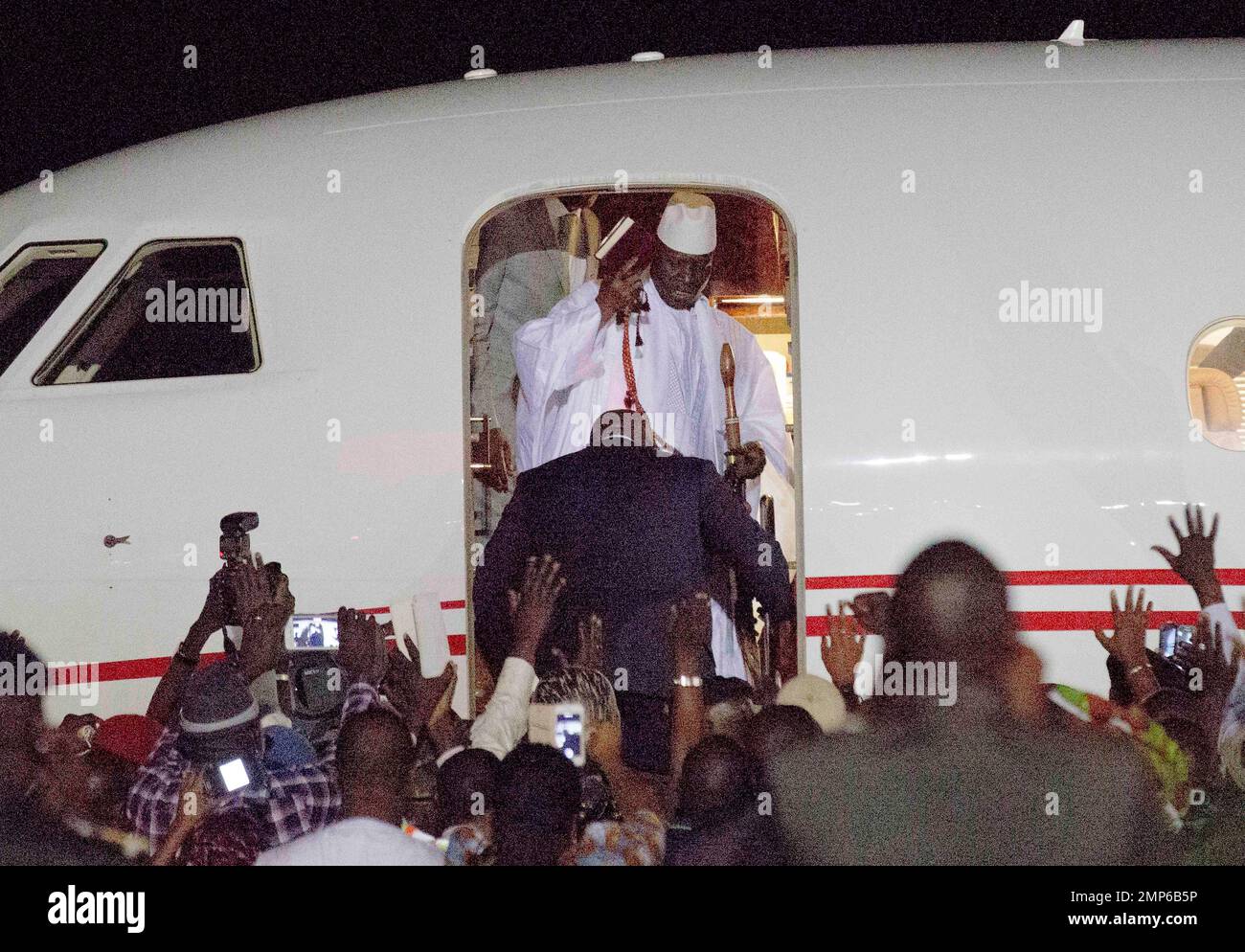 FILE - In this Saturday Jan. 21, 2017 file photo, Gambia's defeated leader Yahya Jammeh, top wearing white, waves to supporters as he goes into exile from Gambia's capital Banjul airport. In the year since the world marvelled at the fall of African dictator Jammeh, the tiny nation of Gambia has risen from the shadows of his "rule of fear" with its arbitrary arrests, enforced disappearances and extrajudicial killings. (AP Photo/Jerome Delay, File) Banque D'Images