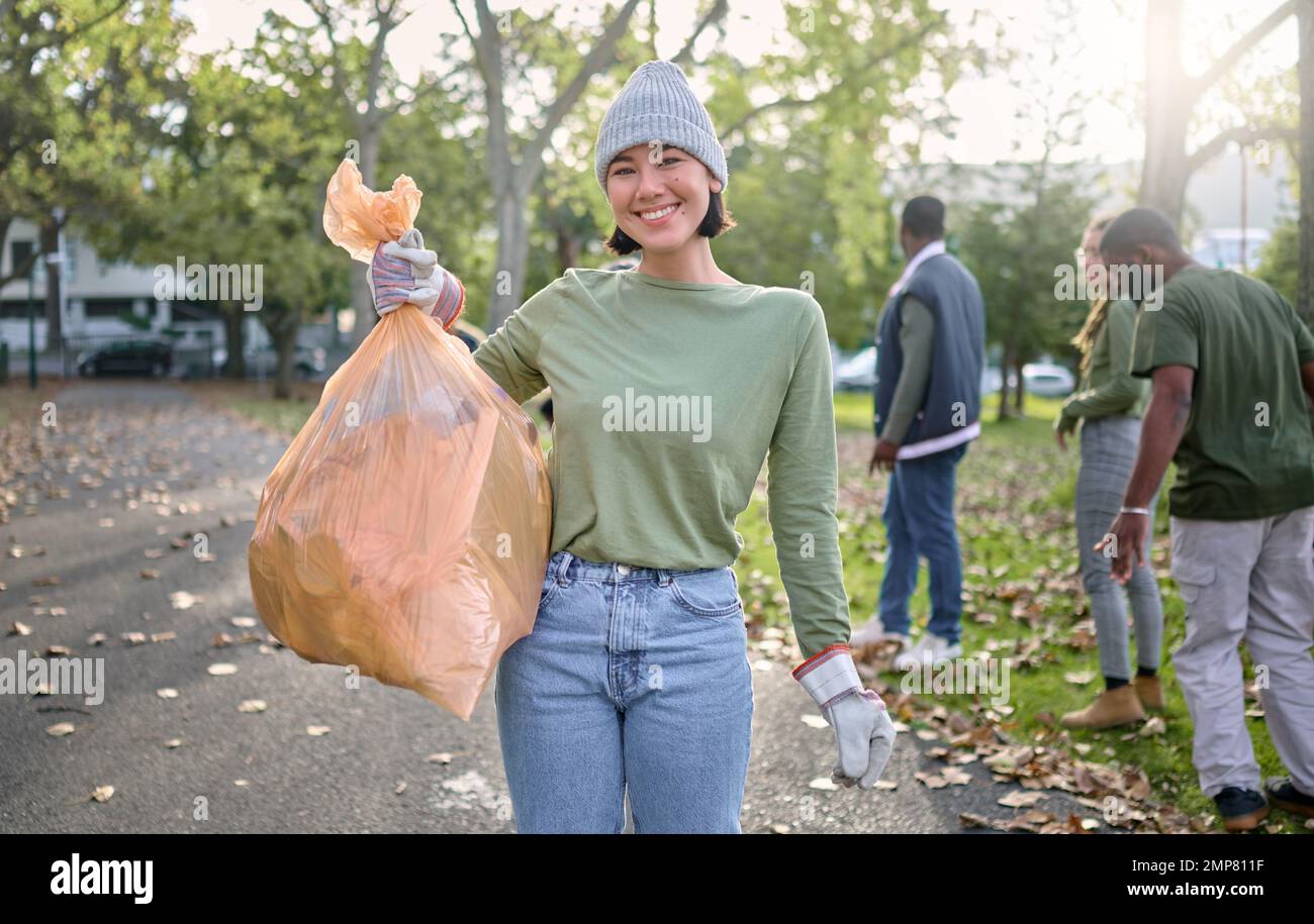 Sac en plastique, parc et femme heureuse en portrait de nettoyage pour le jour de la terre, le service communautaire ou le soutien bénévole. Recyclage, déchets ou déchets objectifs de Banque D'Images