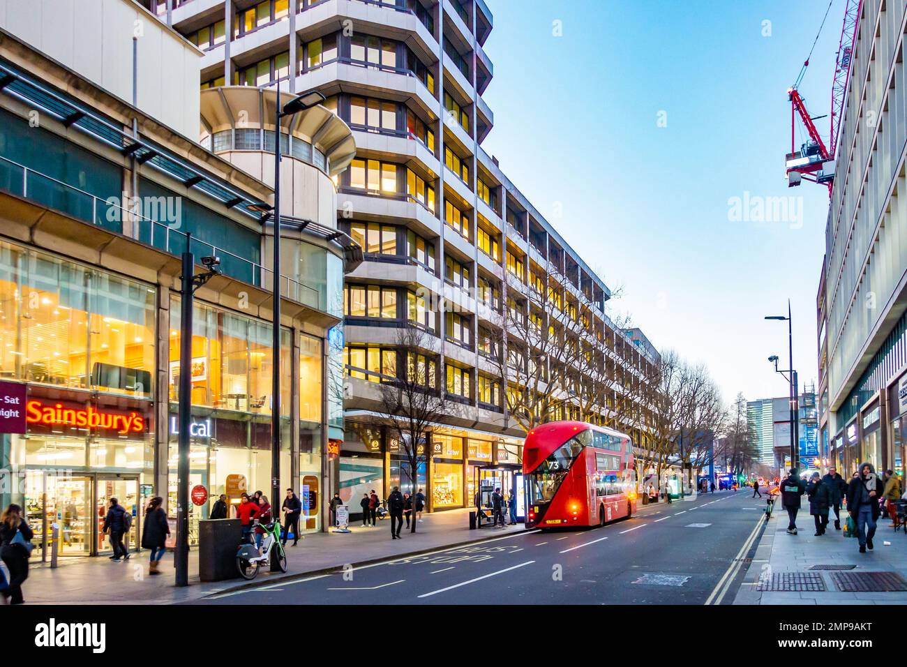 Une vue sur Tottenham court Road à Londres, Royaume-Uni en début de soirée avec les lumières des magasins et des bureaux éclairant la scène. Banque D'Images