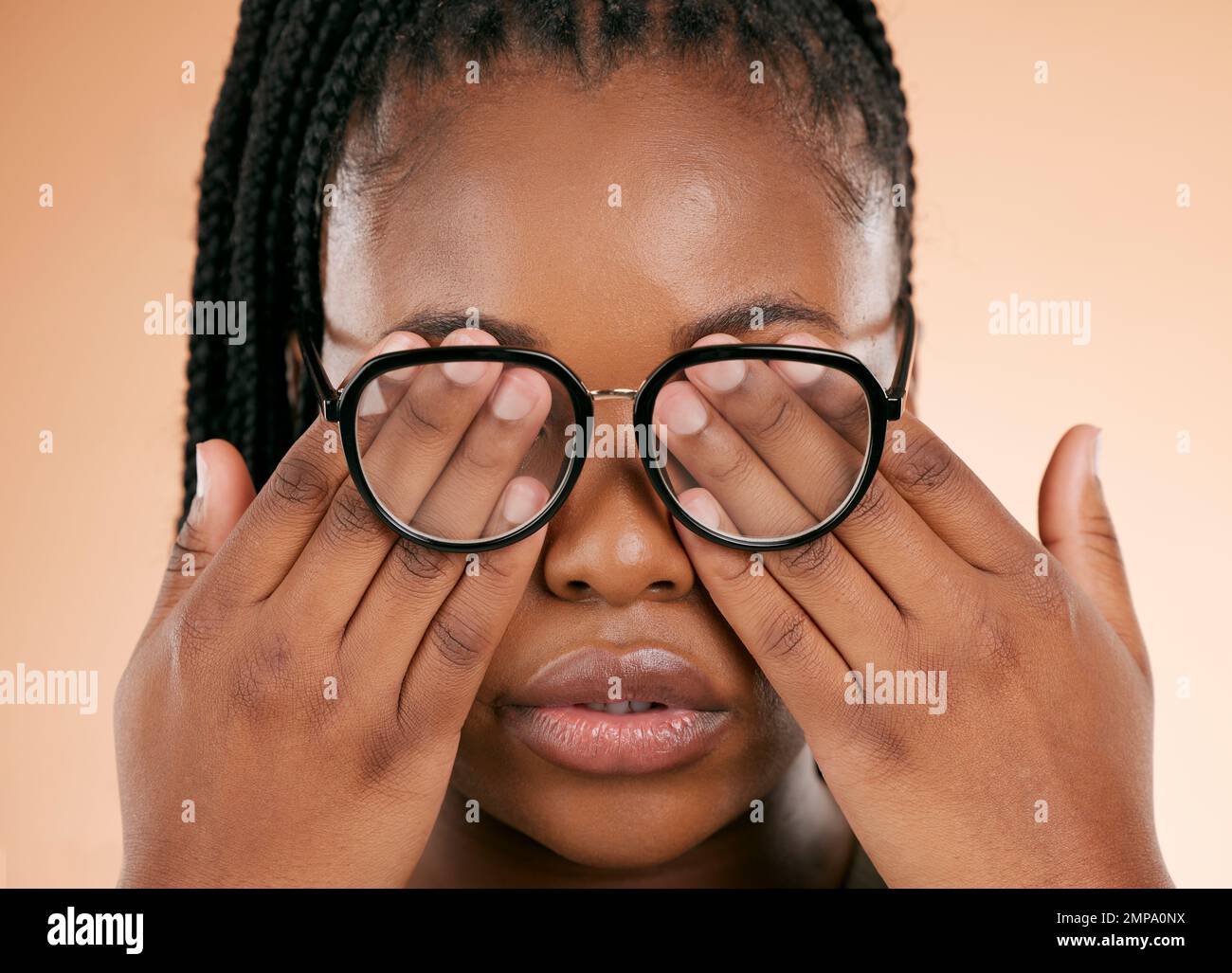 Mains, santé des yeux ou lunettes avec une femme noire en studio sur un fond beige couvrant son visage. Vision, aveugle et couverture avec une femme à l'intérieur de Banque D'Images