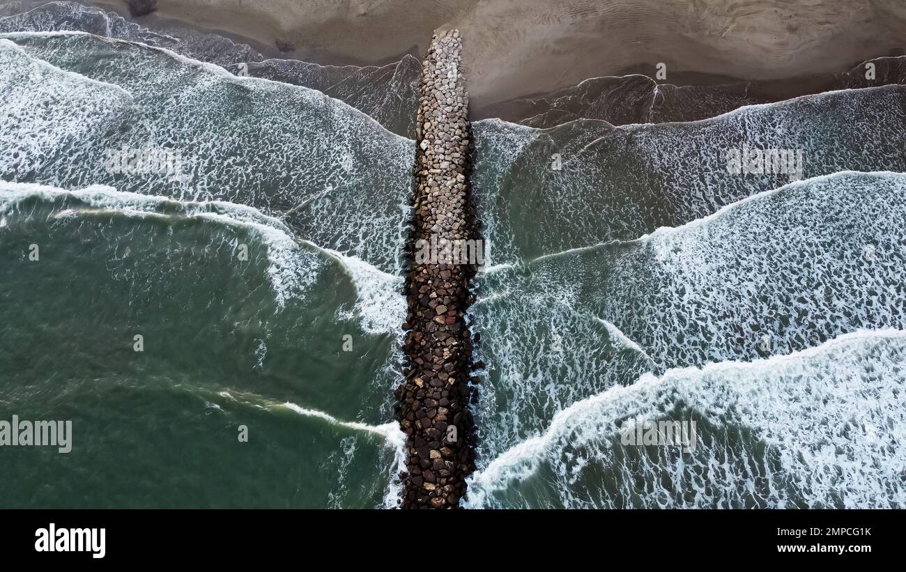 Vue aérienne de dessus Drone vidéos des vagues de l'océan atteignant le brise-lames de pierre de la rive. Banque D'Images Vue aérienne de dessus Drone vidéos des vagues de l'océan atteignant le brise-lames de pierre de la rive. Banque D'Images