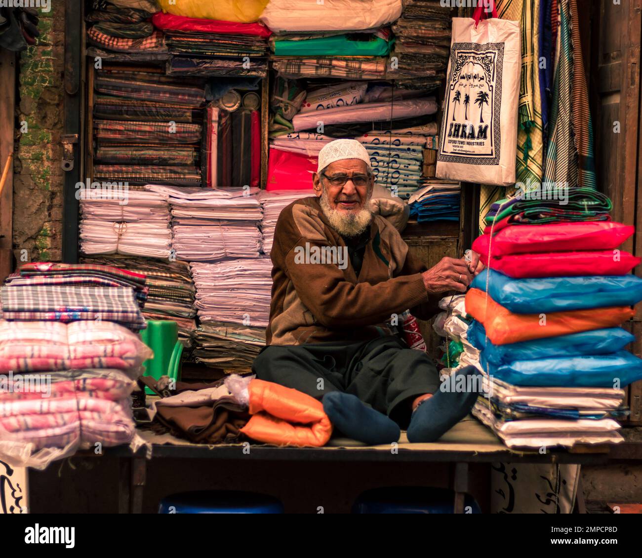 Lahore Pakistan 2020, un vieil homme qui vend des chiffons dans sa petite boutique de tissus dans la ville fortifiée de Lahore, un vieil homme souriant et regardant dans la caméra Banque D'Images