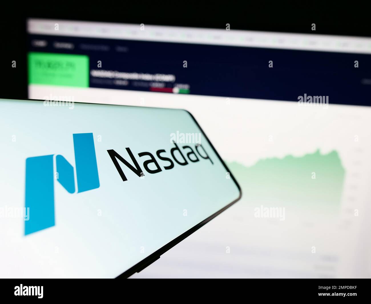 Téléphone mobile avec logo de la bourse américaine Nasdaq sur l'écran en face du site Web d'affaires. Mise au point au centre-gauche de l'écran du téléphone. Banque D'Images