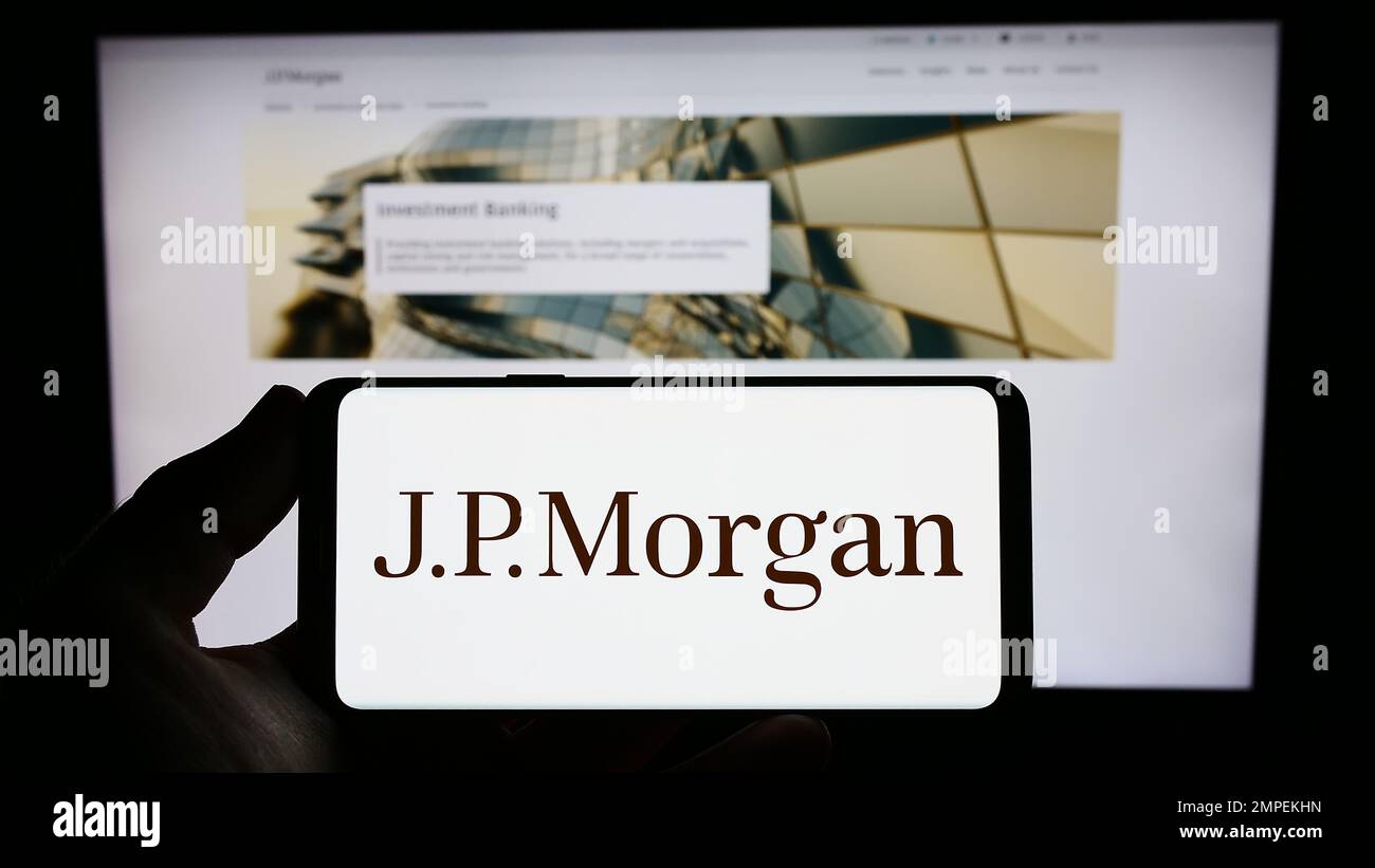 Personne détenant un smartphone portant le logo de la société américaine de services financiers J.P. Morgan Co. À l'écran devant le site Web. Mise au point sur l'affichage du téléphone. Banque D'Images
