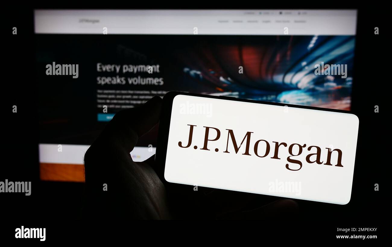 Personne tenant un téléphone portable portant le logo de la société américaine de services financiers J.P. Morgan Co. Sur l'écran en face de la page Web. Mise au point sur l'affichage du téléphone. Banque D'Images