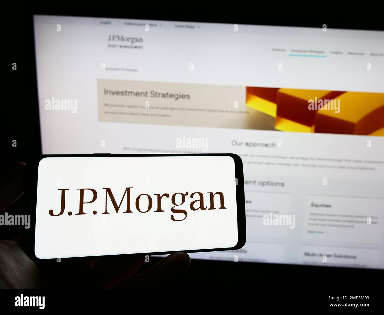 Personne tenant un téléphone cellulaire avec le logo de la société américaine de services financiers J.P. Morgan Co. À l'écran en face de la page Web. Mise au point sur l'affichage du téléphone. Banque D'Images