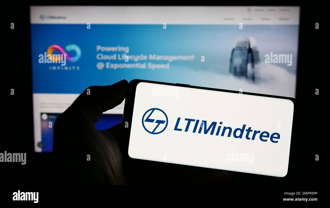 Personne tenant un téléphone cellulaire avec le logo de la société indienne DE TI LTIMIDTree Limited à l'écran devant la page Web d'affaires. Mise au point sur l'affichage du téléphone. Banque D'Images