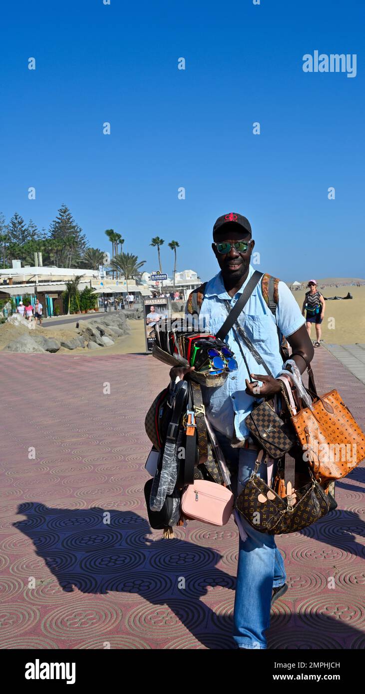 Vendeur de trottoirs vendant des sacs, des chapeaux, des marchandises le long de la Promenade sous le phare le long de la plage de Maspalomas Banque D'Images