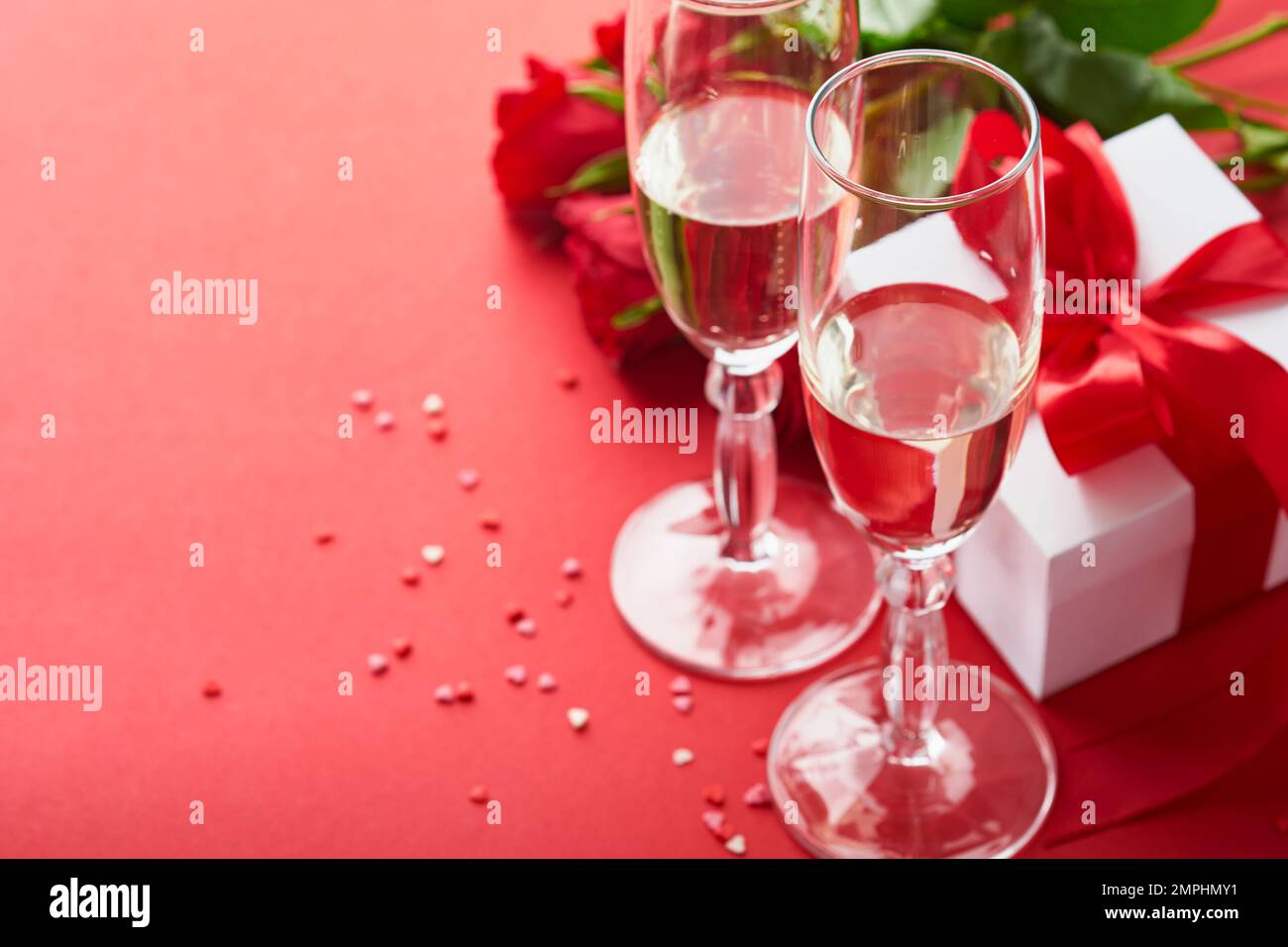 Concept de la Saint-Valentin ou dîner romantique. Décor romantique de table, argenterie, verres à vin, boîte cadeau, roses et symbole de l'amour coeur rouge sur le dos rouge Banque D'Images
