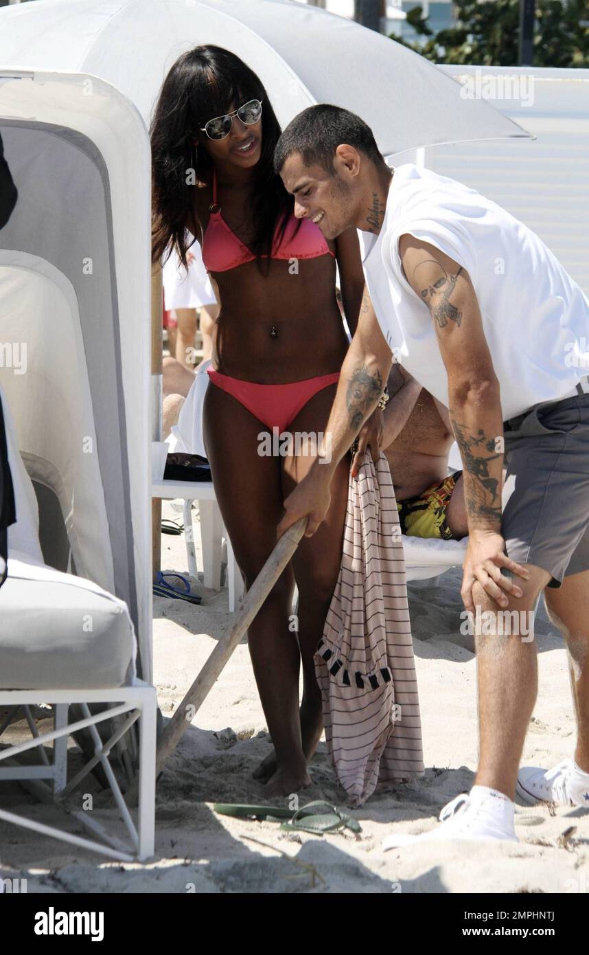 Alexandra Burke porte un bikini couleur pêche à la plage comme elle aime un autre jour au soleil. Tout en faisant une promenade sur la plage dans une robe longue rayée tendance Burke s'est arrêté pour ramasser des coquillages avant de prendre un plongeon dans l'eau de refroidissement. Plus tard, la chanteuse a montré ses multiples bracelets perlés comme elle a texté sur son unique téléphone cellulaire clouté. Miami Beach, Floride. 3/7/11 Banque D'Images