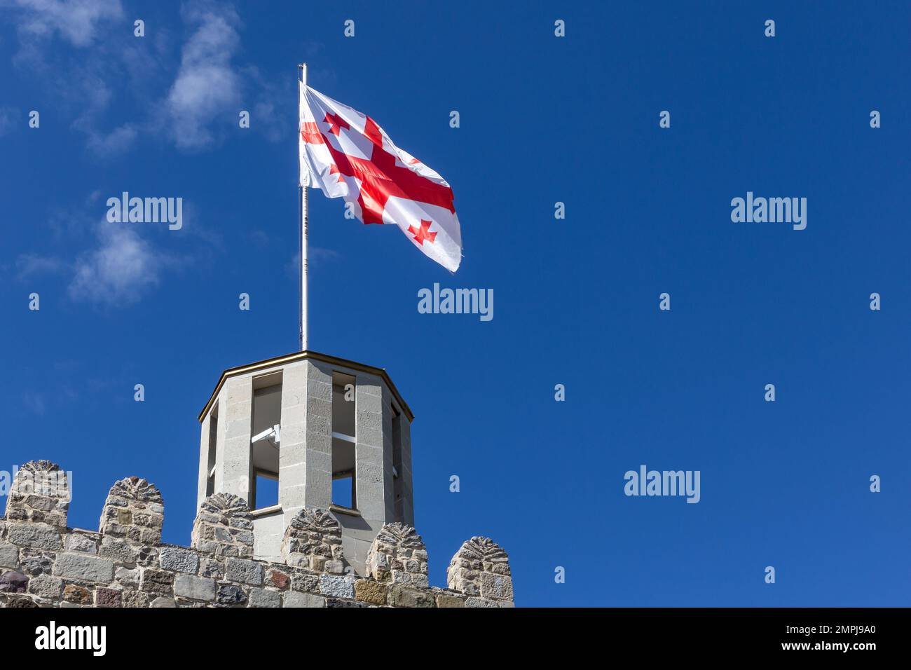 Drapeau national géorgien (drapeau à cinq croix) agitant sur le vent contre un ciel bleu clair au sommet de l'ancienne tour de guet du château d'Akhaltsikhe (Rabati). Banque D'Images